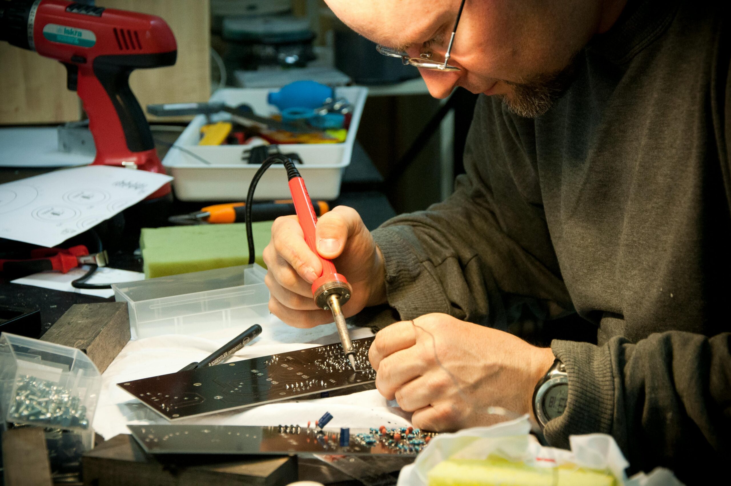 Man aan een werktafel bezig met reparatie van printplaat